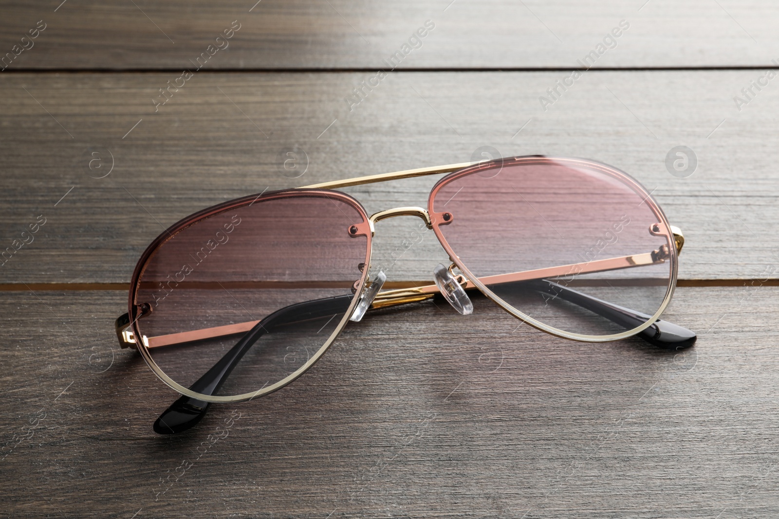 Photo of New stylish sunglasses on wooden table, closeup