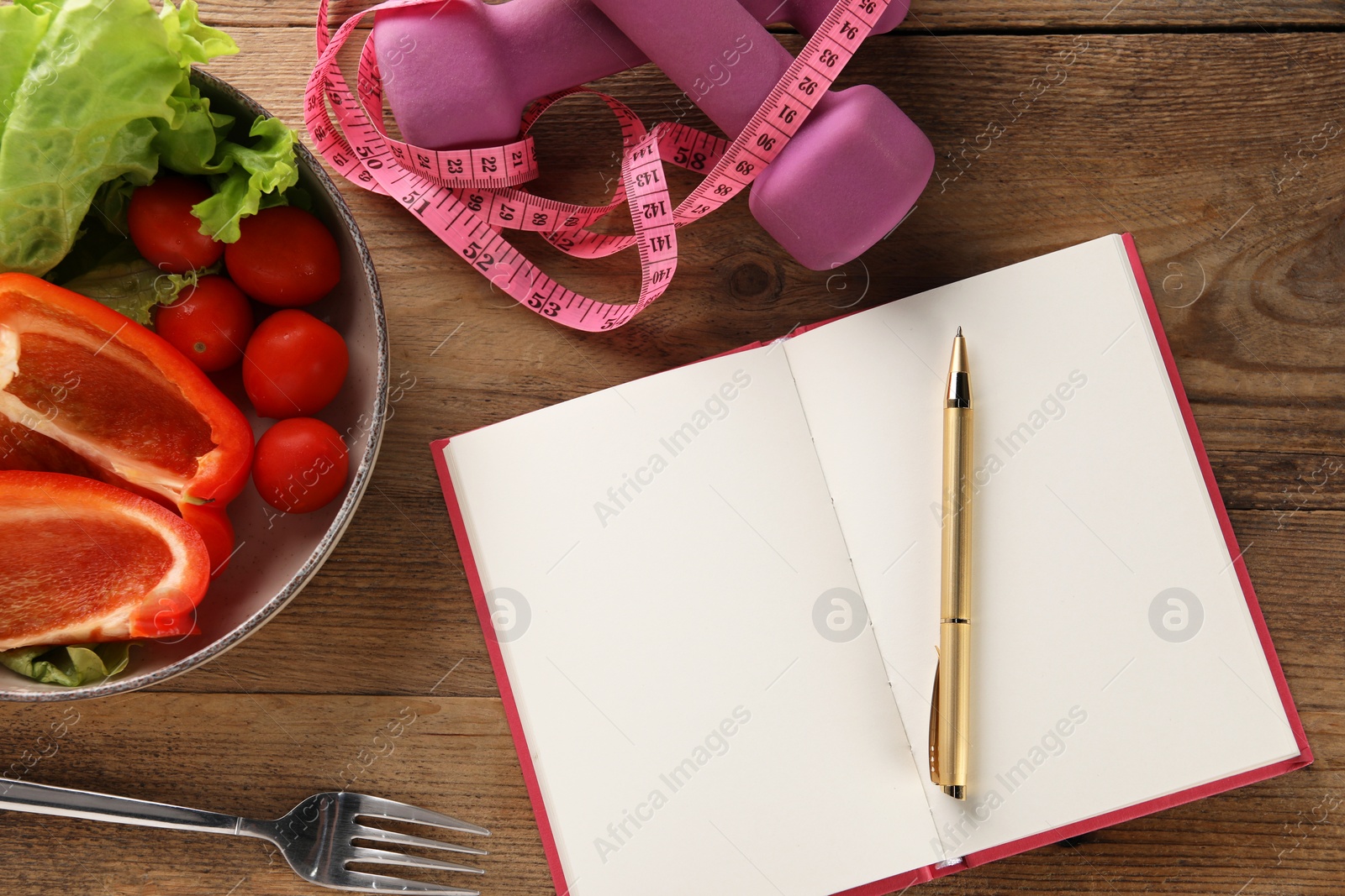 Photo of Healthy diet. Vegetables, fork, notebook, dumbbells and measuring tape on wooden table, flat lay with space for text