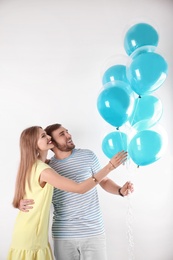 Young couple with air balloons on white background