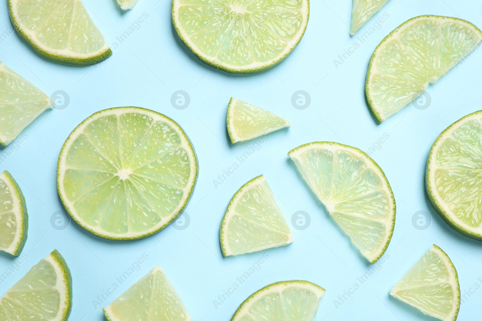 Photo of Juicy fresh lime slices on light blue background, flat lay