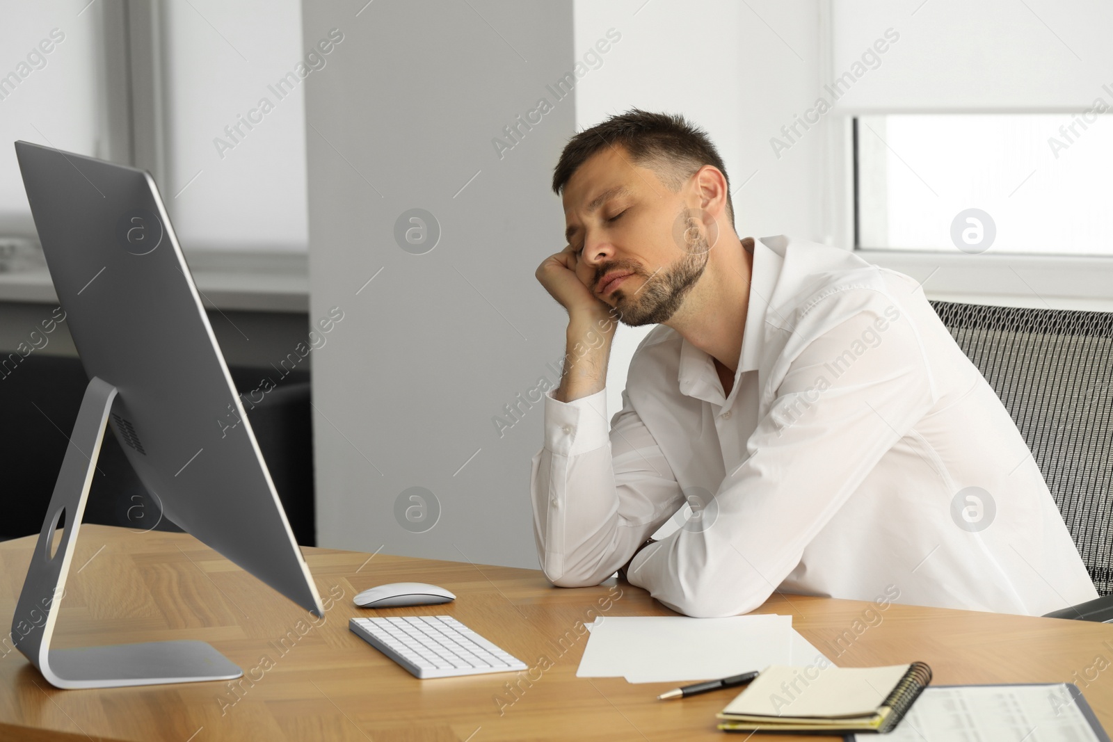 Photo of Sleepy man snoozing at workplace in office