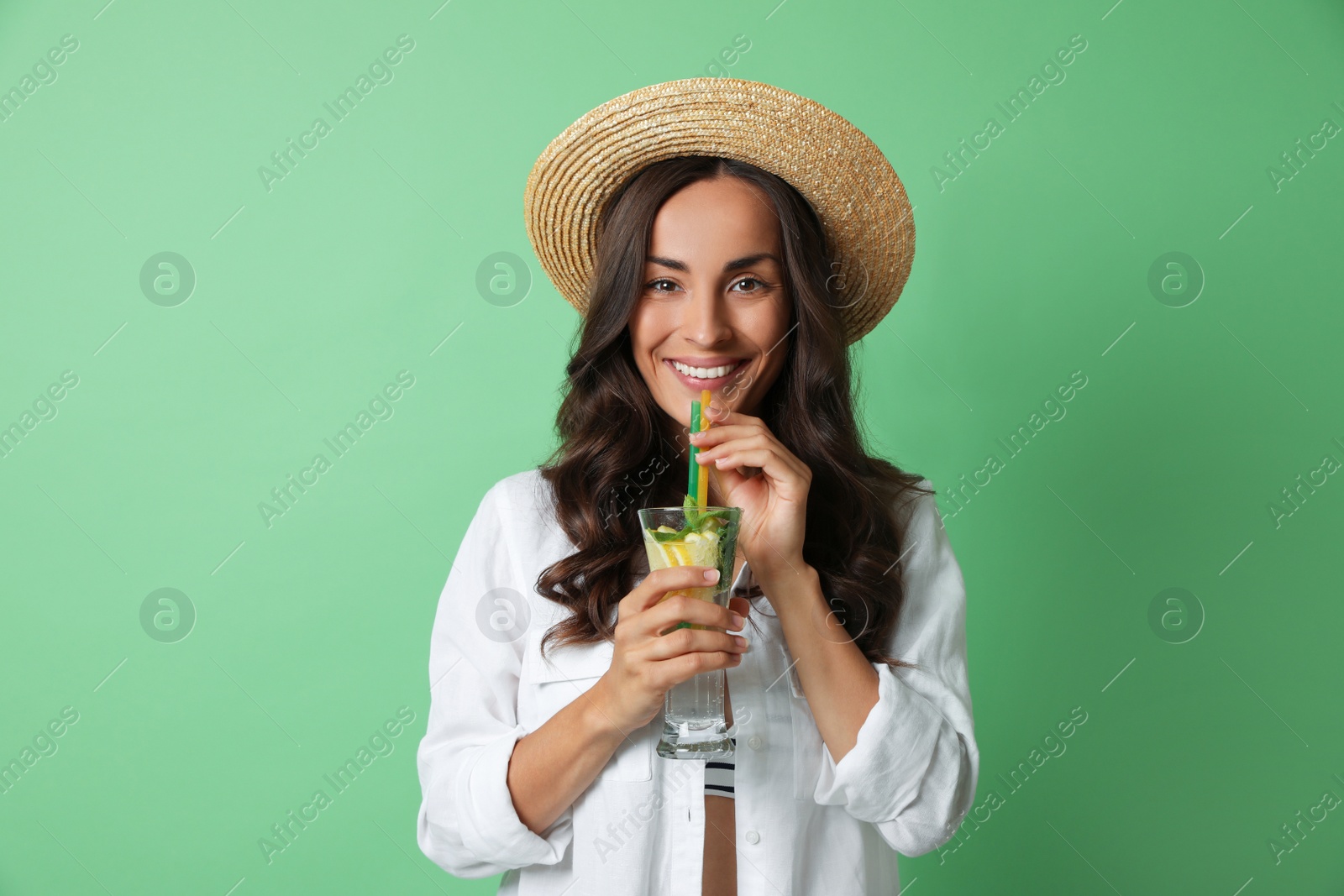 Photo of Young woman with refreshing drink on green background