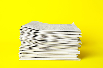 Photo of Stack of newspapers on yellow background. Journalist's work