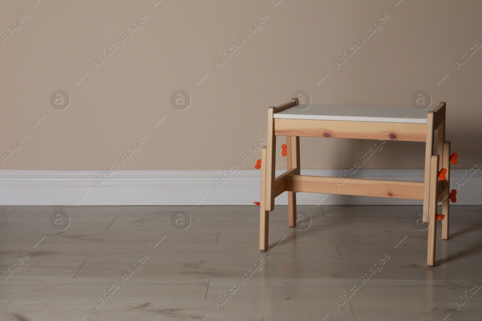 Photo of Stylish wooden stool near beige wall indoors. Space for text