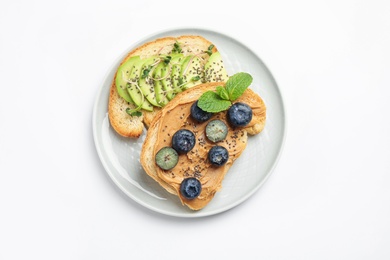 Photo of Plate of tasty toasts with avocado, blueberries and chia seeds on white background, top view
