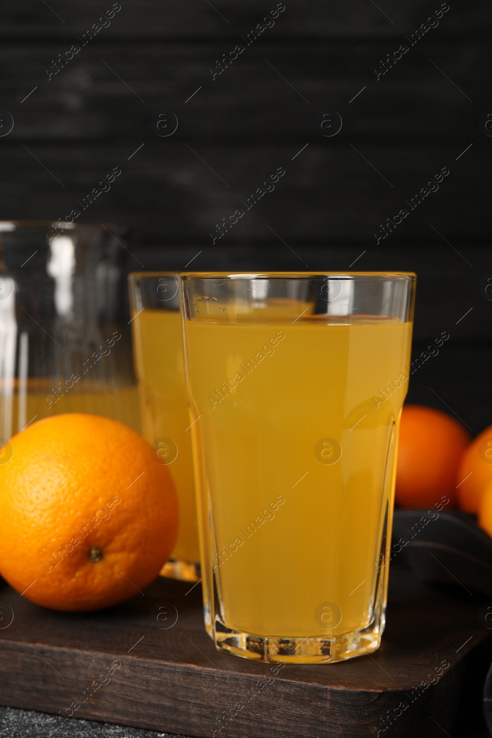 Photo of Many ripe oranges and fresh juice on dark grey table