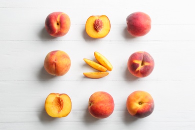 Fresh sweet peaches on white wooden table, flat lay