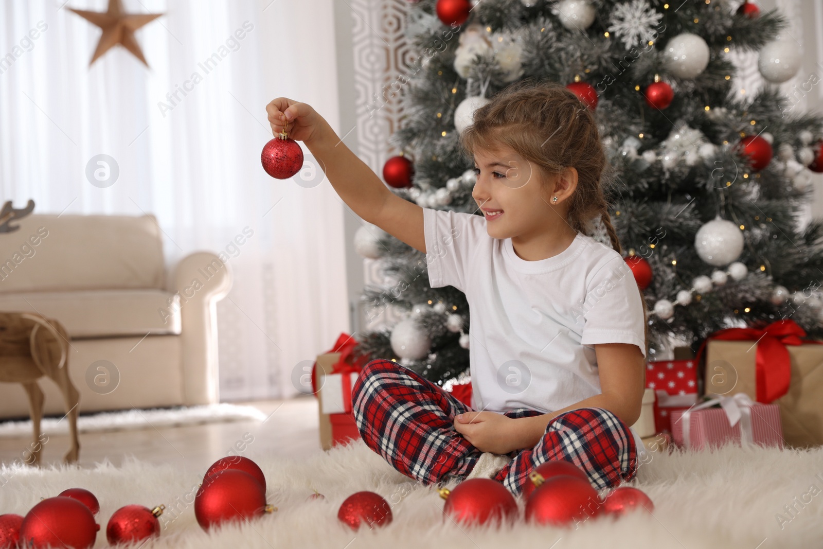 Photo of Cute little girl with box of Christmas balls at home