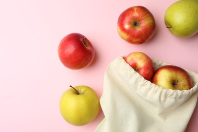 Photo of Cotton eco bag and apples on pink background, flat lay