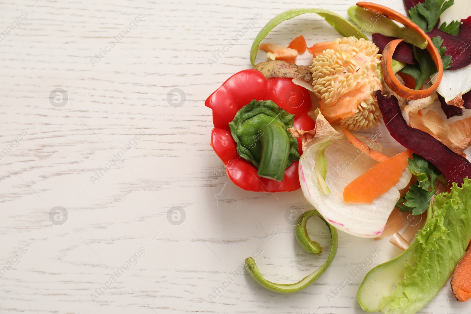 Photo of Peels of fresh vegetables on white wooden table, flat lay. Space for text