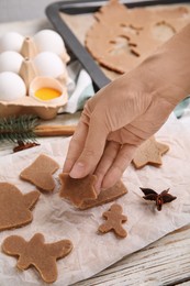 Photo of Woman making gingerbread Christmas cookies at white wooden table, closeup