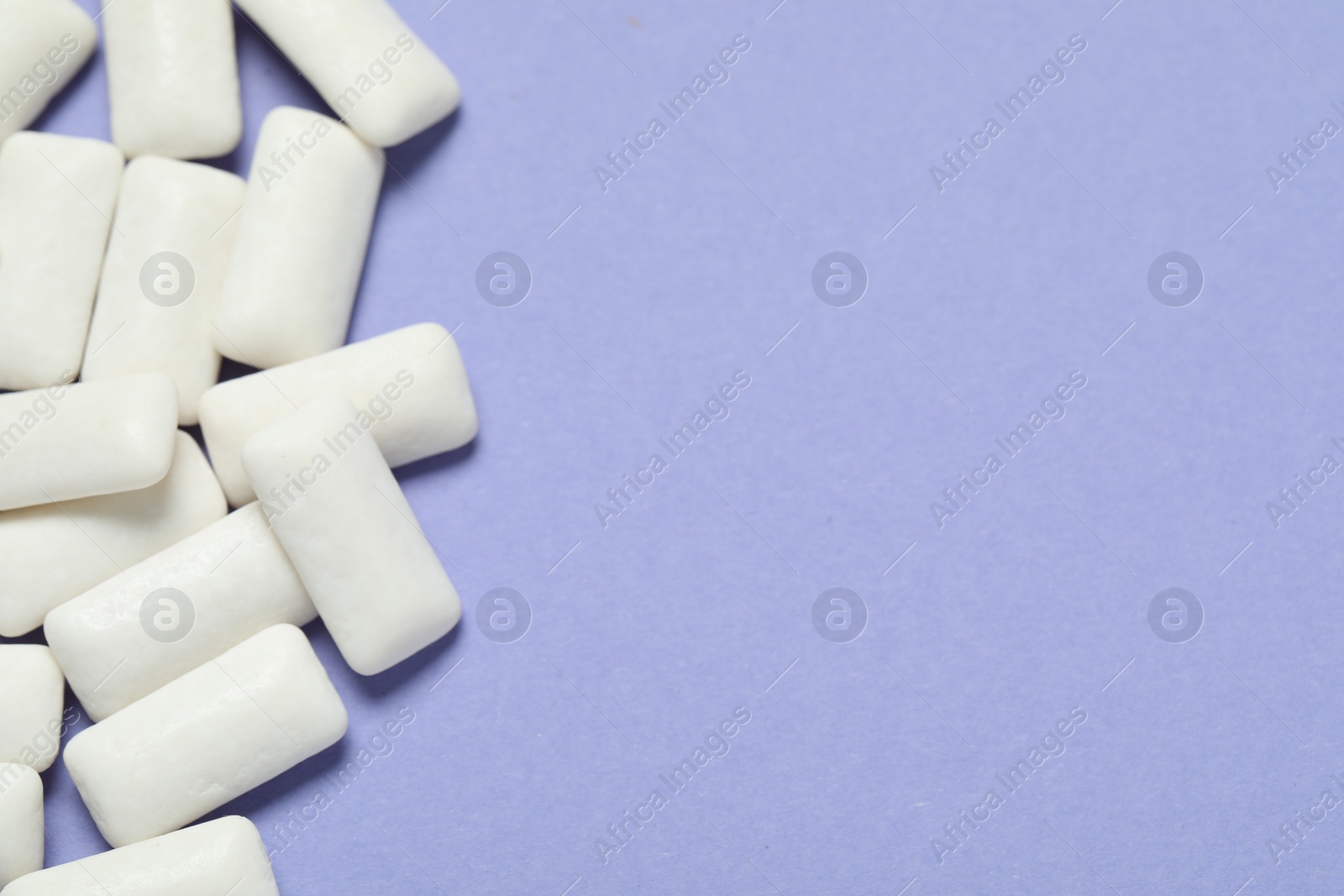 Photo of Tasty white chewing gums on light blue background, top view. Space for text