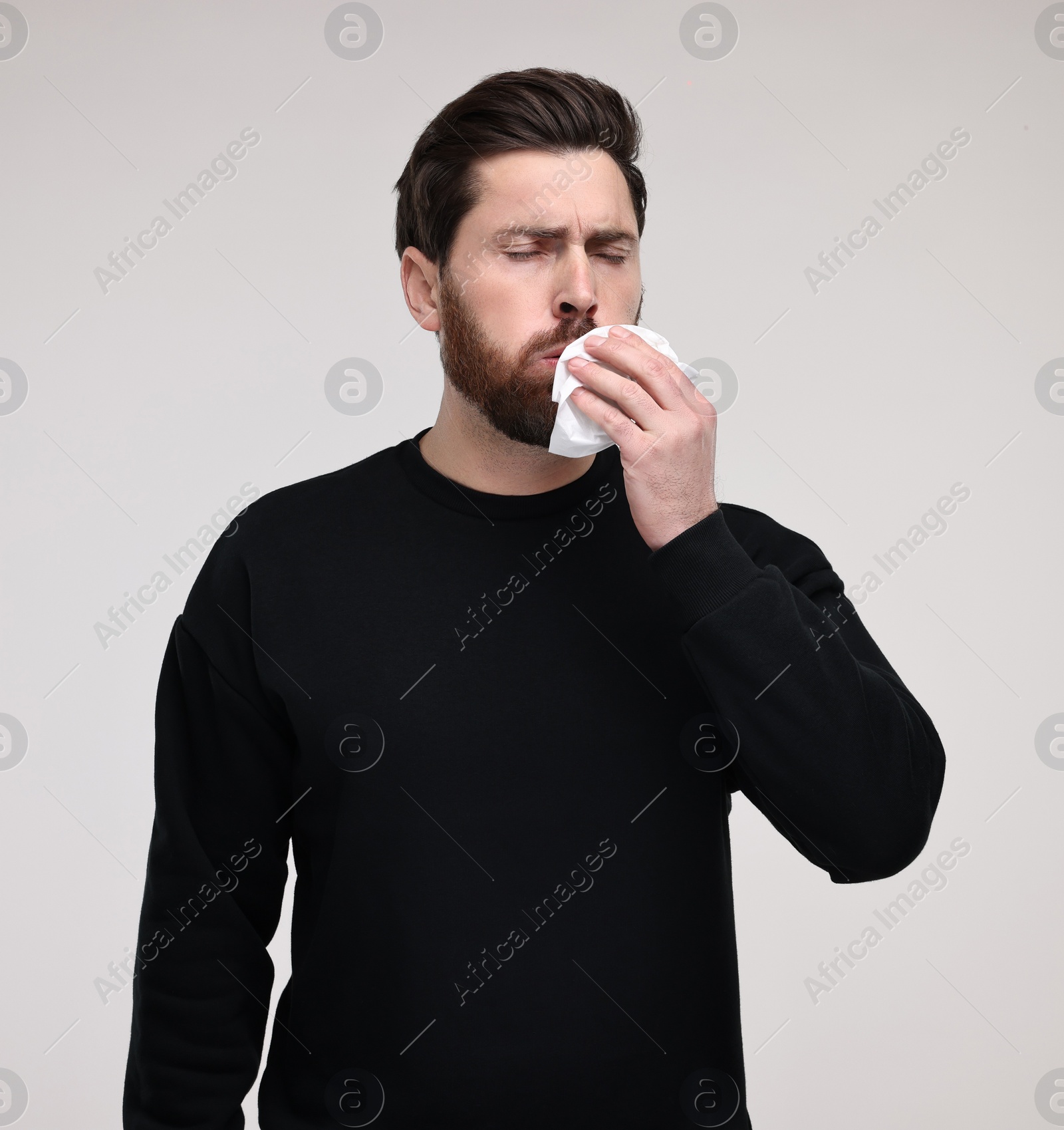 Photo of Sick man with tissue coughing on light grey background