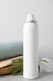 Photo of Dry shampoo spray, green twig and towel on light grey marble table