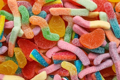 Many different tasty jelly candies as background, top view