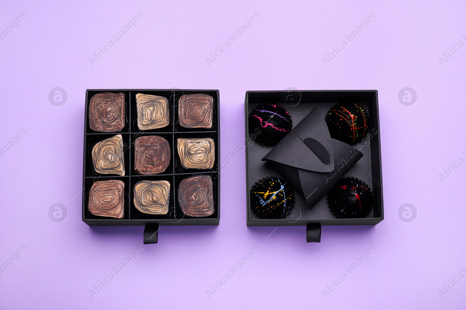 Photo of Boxes of tasty chocolate candies on violet background, flat lay