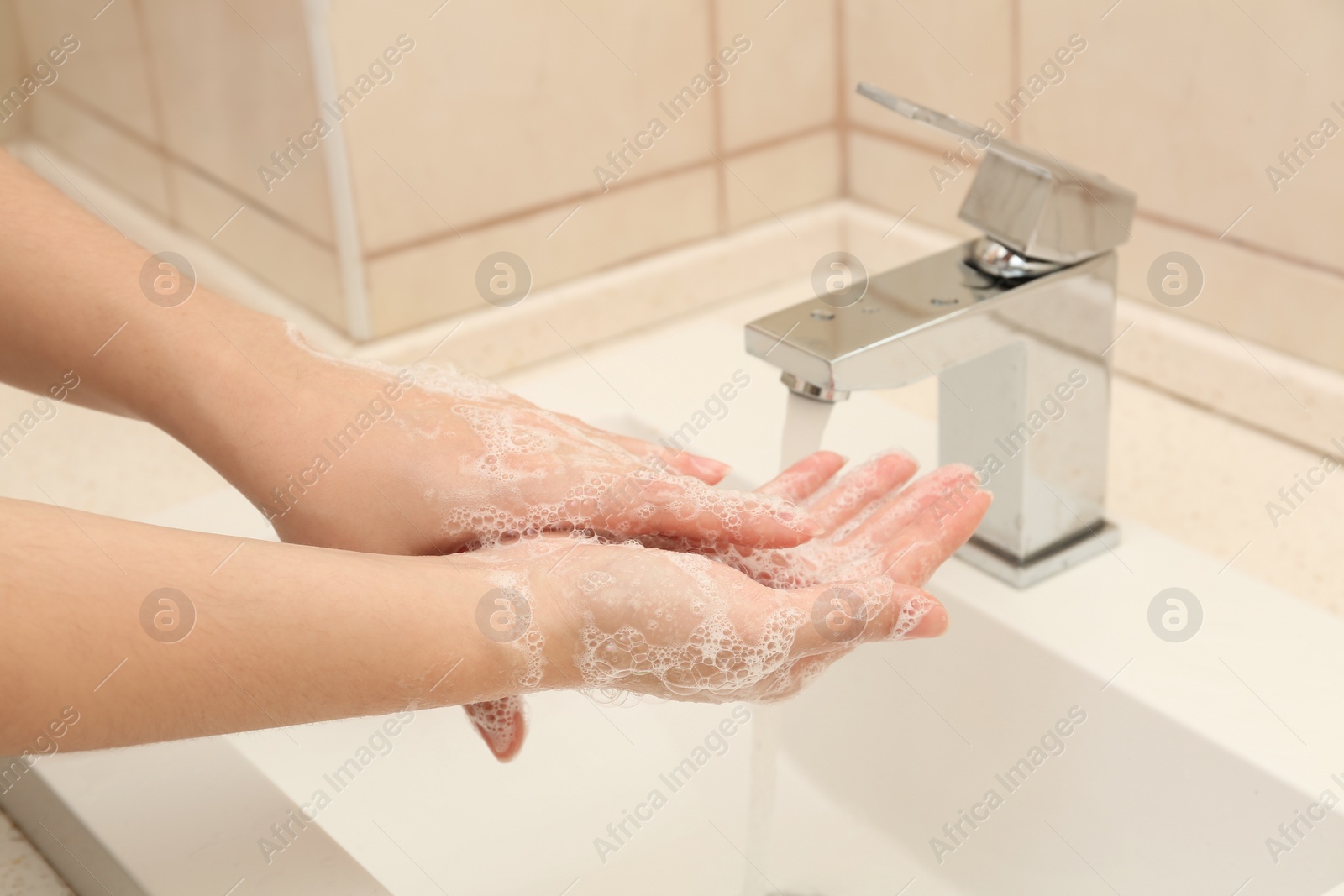 Photo of Woman washing hands with antiseptic soap in bathroom, closeup