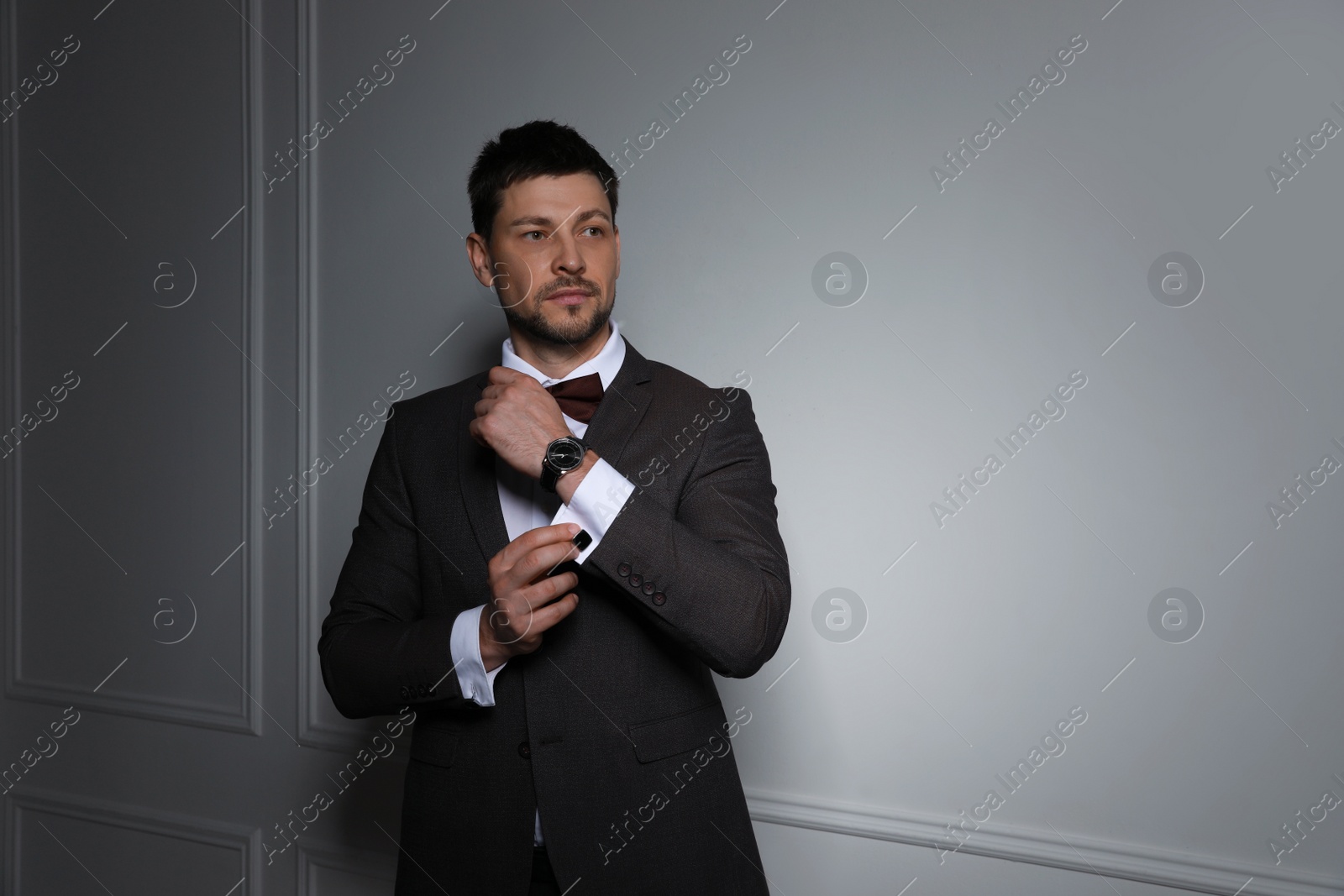 Photo of Man wearing stylish suit and cufflinks near white wall