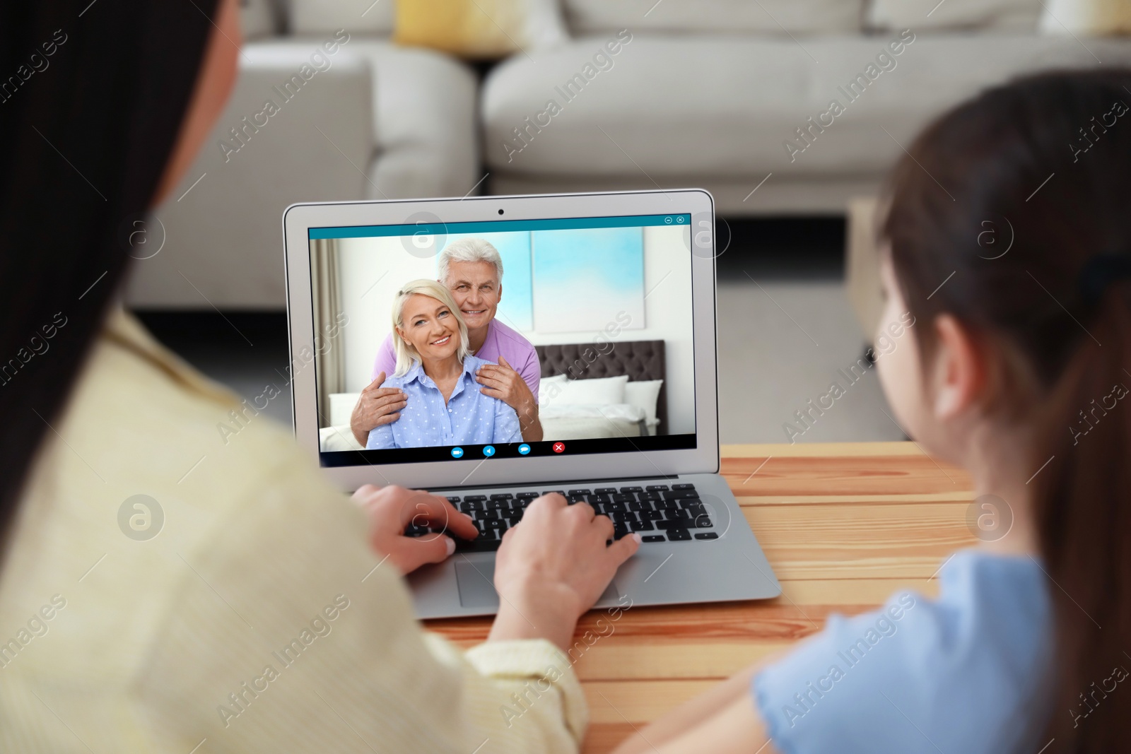 Image of Mother and daughter having online meeting with family members via videocall application at home