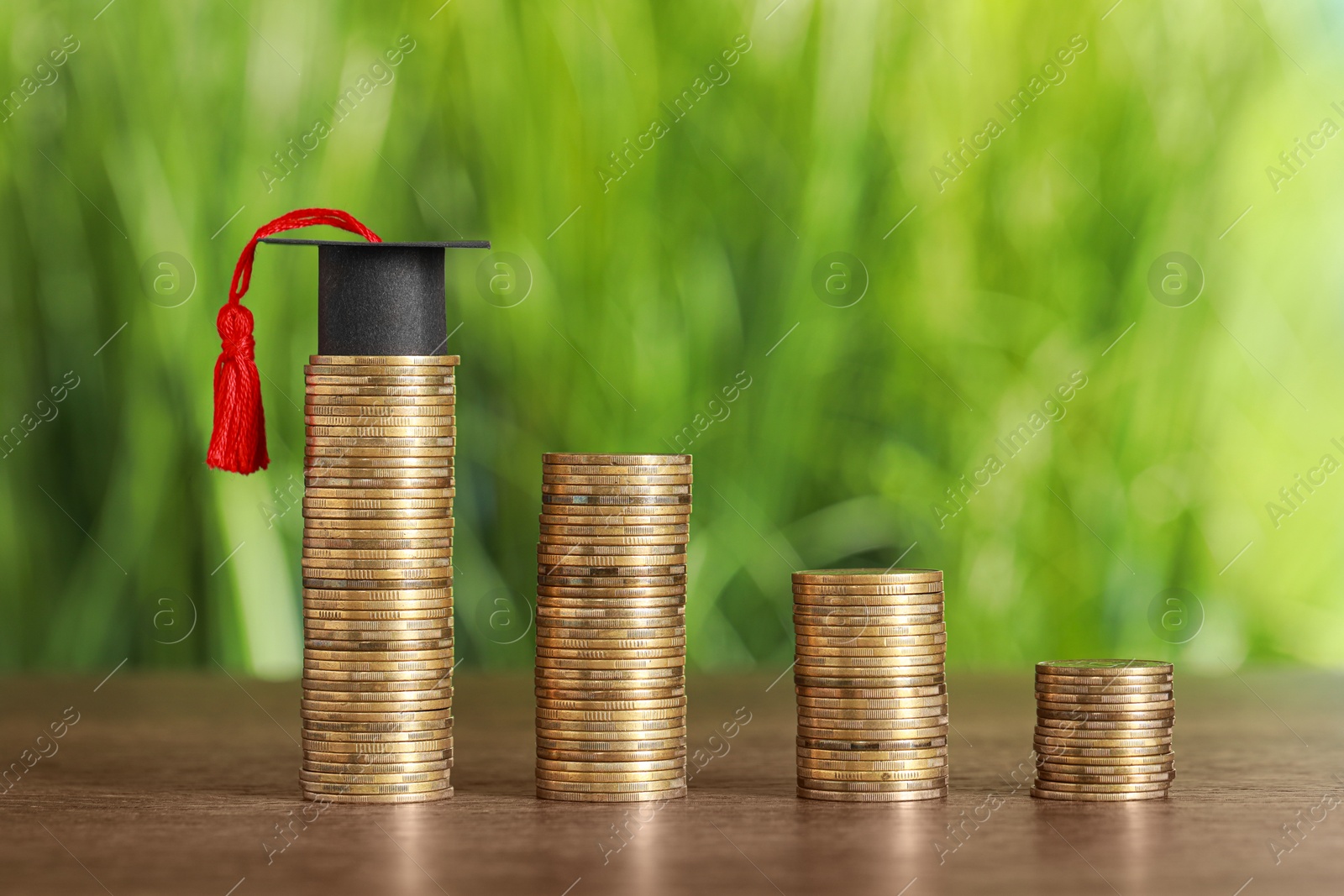 Photo of Scholarship concept. Coins and student graduation cap on wooden table