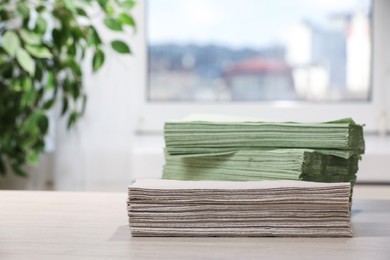 Photo of Paper napkins on wooden table indoors. Space for text