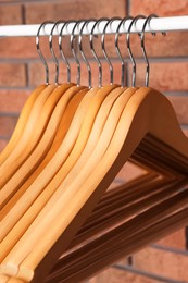 Photo of Wooden clothes hangers on rail near red brick wall, closeup