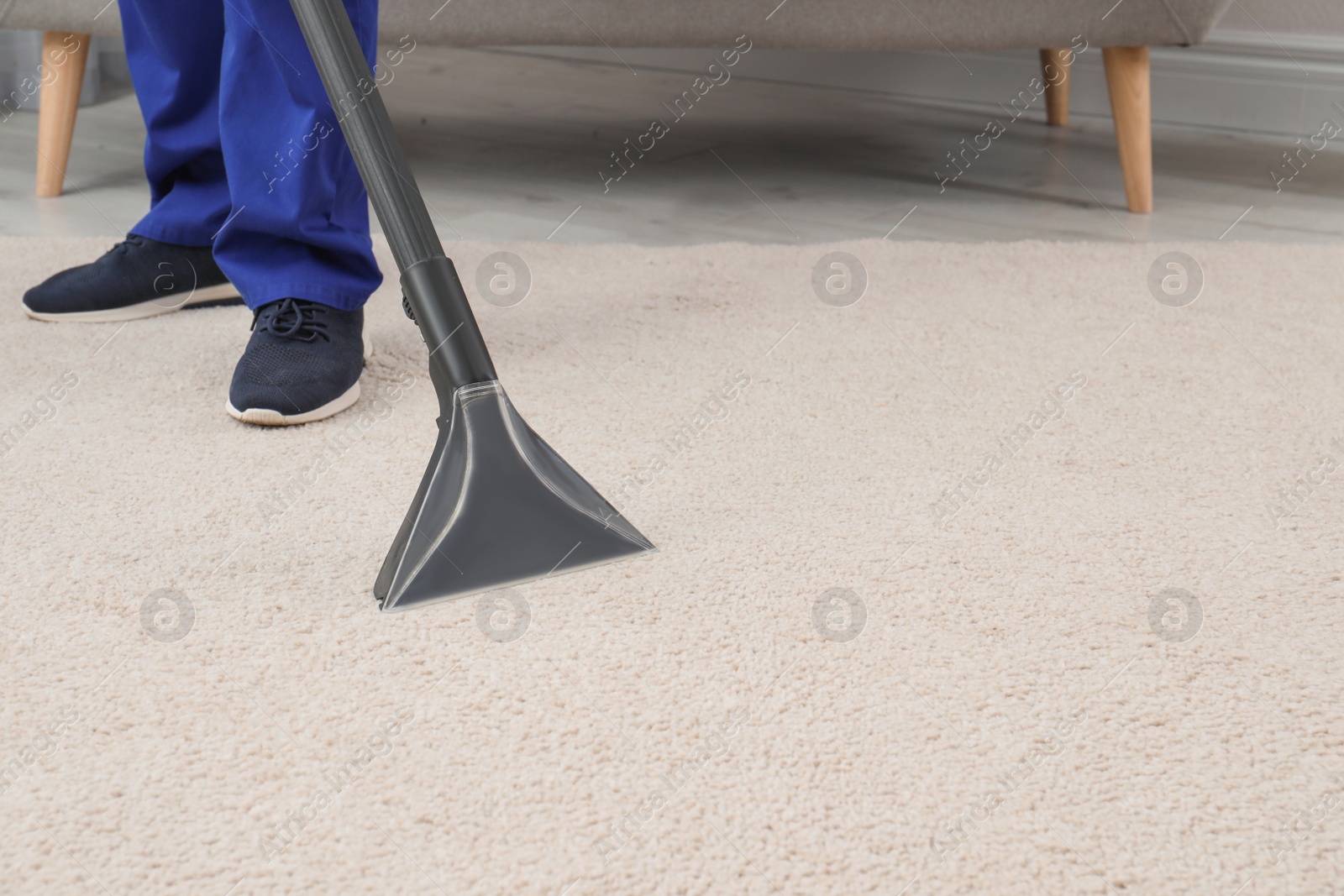 Photo of Man removing dirt from carpet with vacuum cleaner indoors, closeup. Space for text