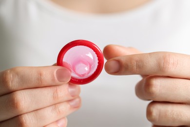 Photo of Woman holding unpacked condom, closeup. Safe sex