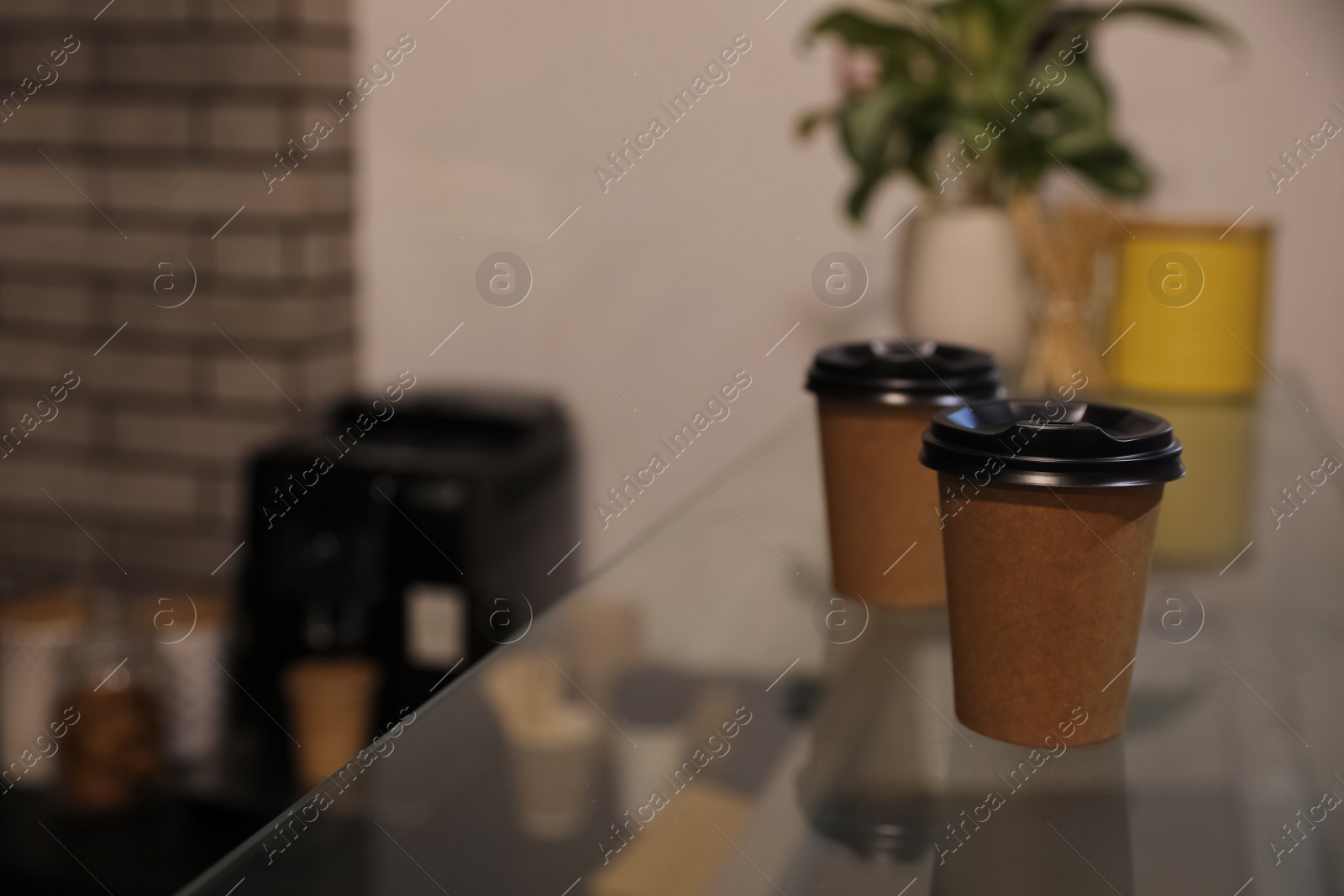 Photo of Takeaway coffee cups with plastic lids on glass table in cafe. Space for text