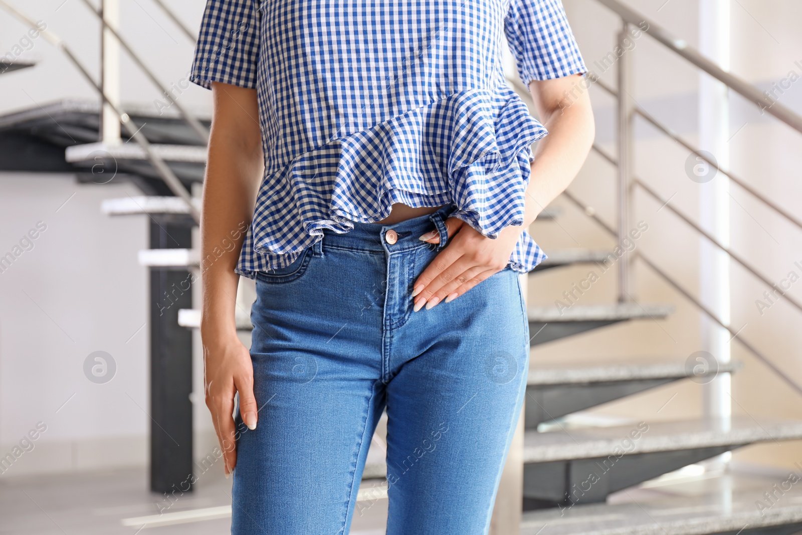 Photo of Young woman in stylish blue jeans indoors