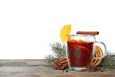 Photo of Composition with glass cup of mulled wine, cinnamon, orange and fir branch on table against white background. Space for text