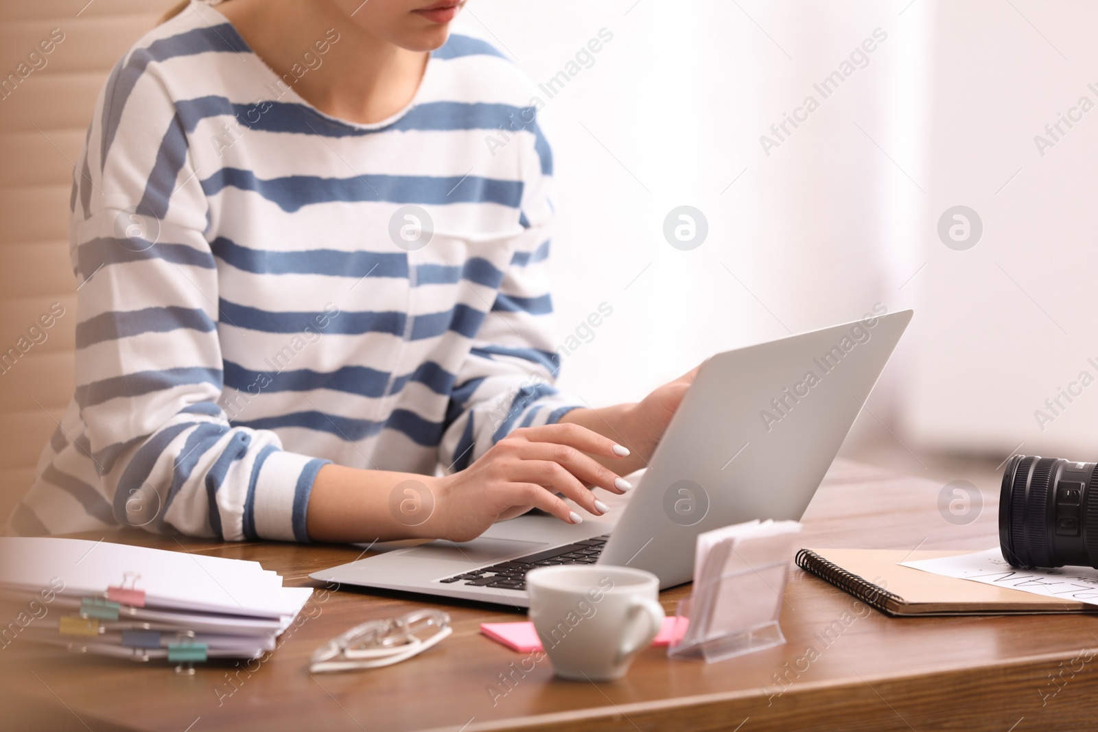 Photo of Young journalist working with laptop in office, closeup