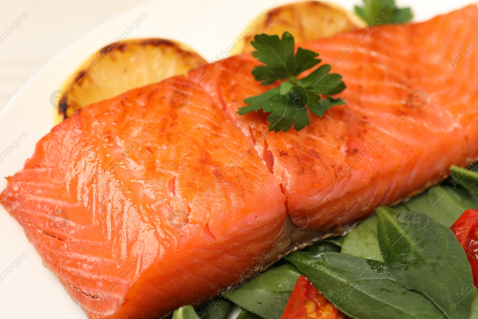 Photo of Tasty grilled salmon with basil and parsley on white plate, closeup