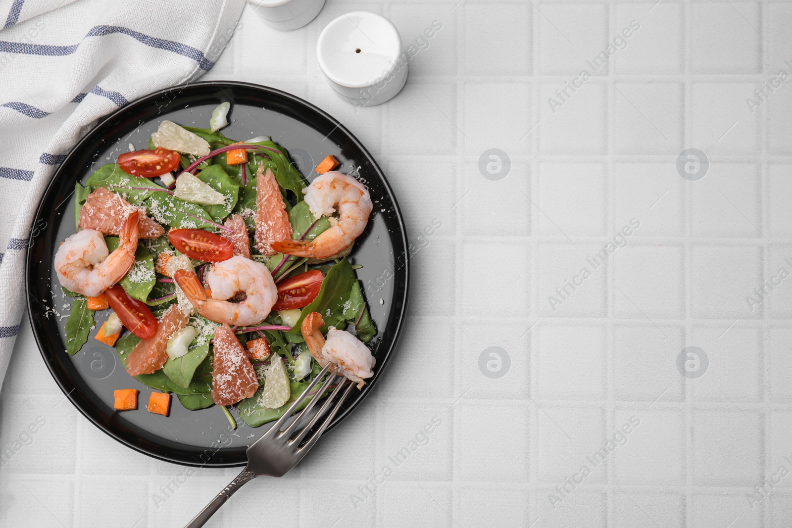 Photo of Delicious salad with pomelo, shrimps and tomatoes on white tiled table, flat lay. Space for text