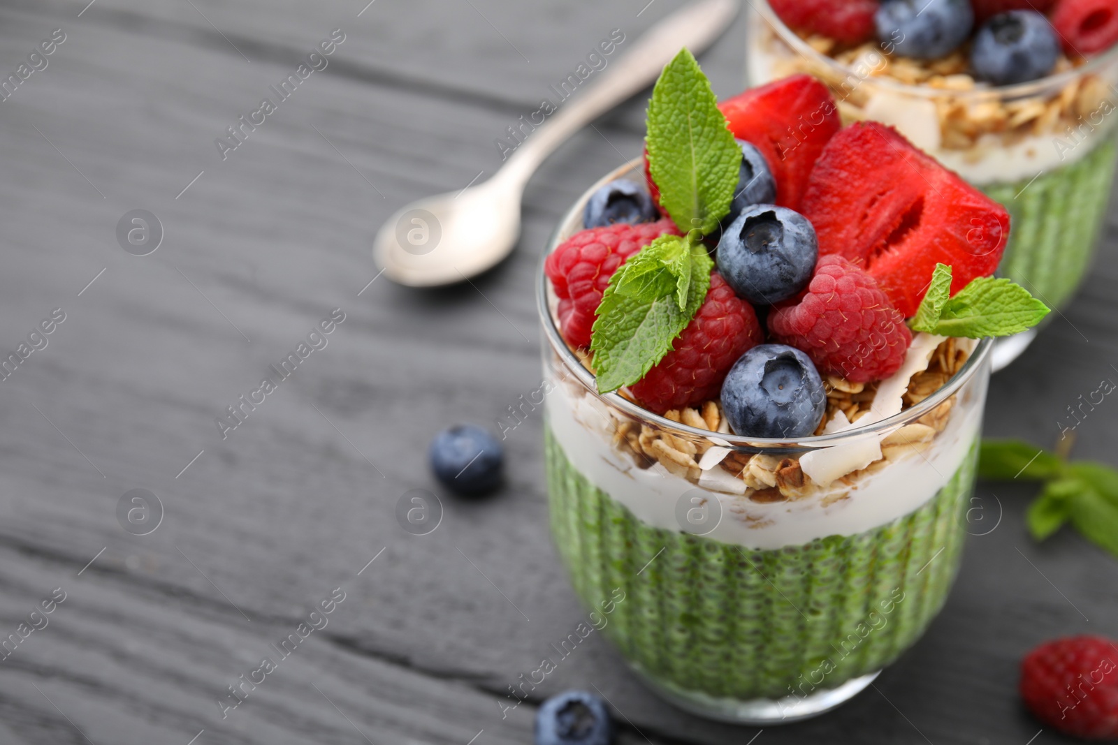 Photo of Tasty matcha chia pudding with oatmeal and berries on grey wooden table, closeup. Space for text. Healthy breakfast