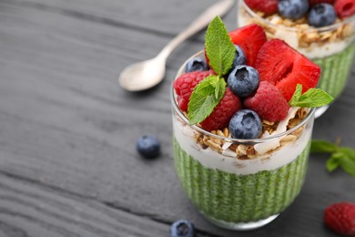 Tasty matcha chia pudding with oatmeal and berries on grey wooden table, closeup. Space for text. Healthy breakfast