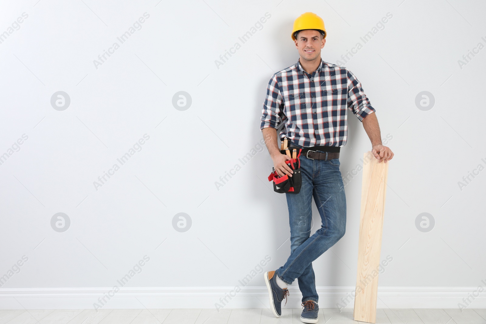 Photo of Handsome carpenter with wooden planks near light wall. Space for text