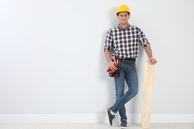Photo of Handsome carpenter with wooden planks near light wall. Space for text