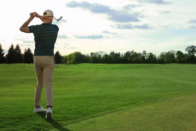 Photo of Man playing golf on green course, back view. Space for text