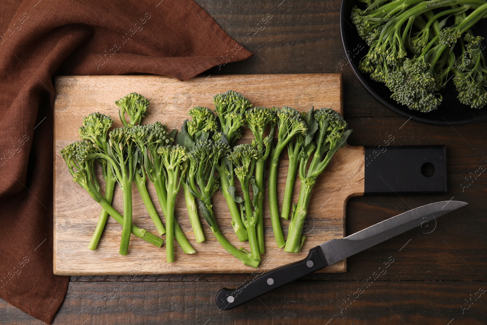 Photo of Fresh raw broccolini and knife on wooden table, flat lay. Healthy food