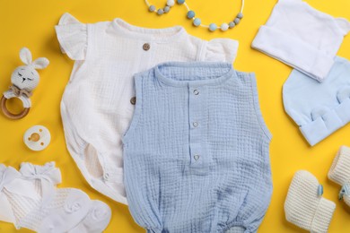 Flat lay composition with baby clothes and accessories on yellow background