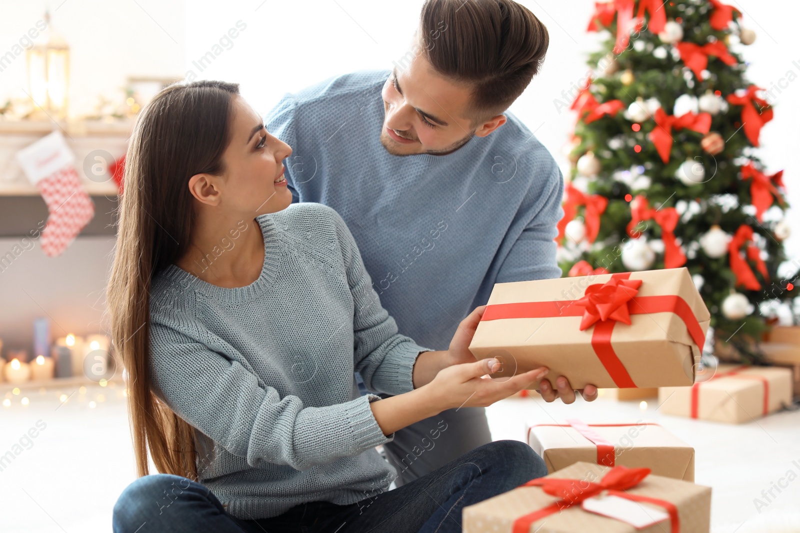 Photo of Young man giving Christmas gift to his girlfriend at home