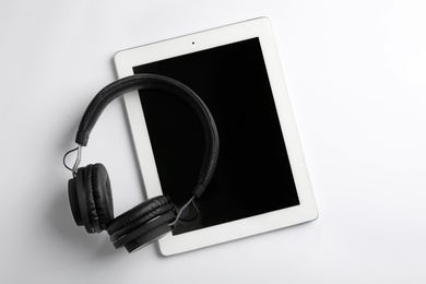 Photo of Stylish headphones and modern tablet on white background, top view