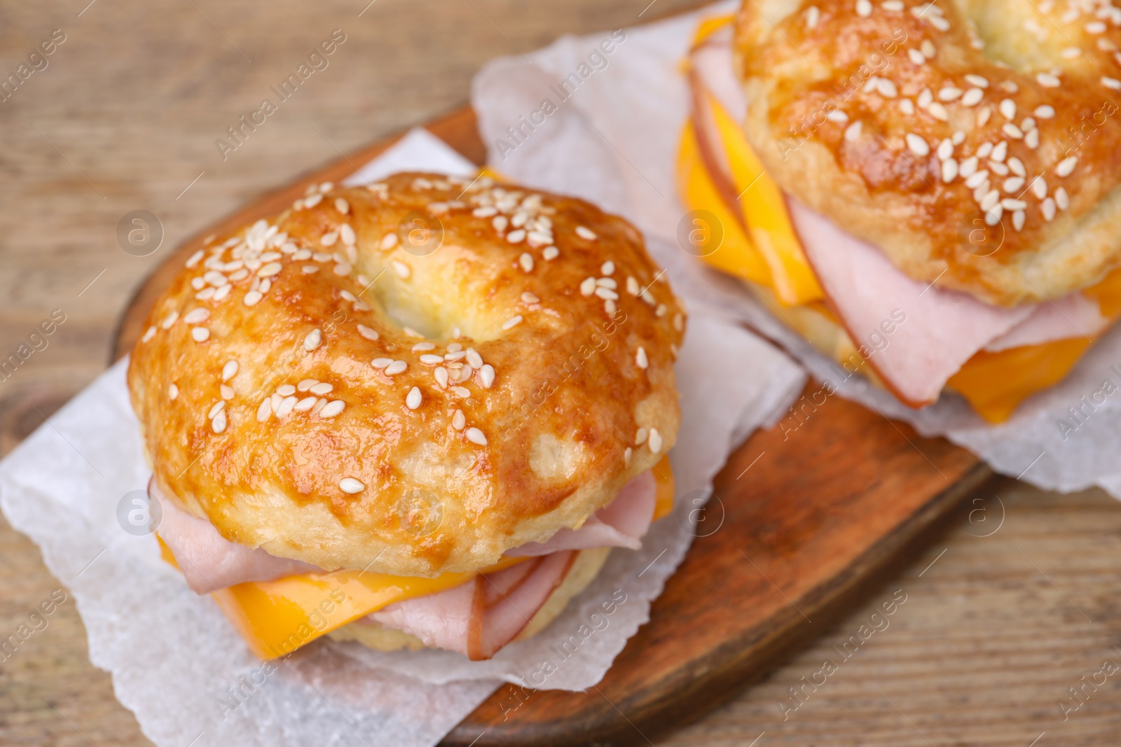Delicious bagels with ham and cheese on wooden table, closeup Photo of Delicious bagels with ham and cheese on wooden table, closeup