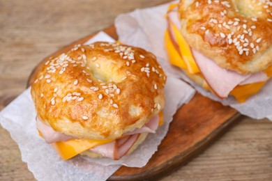 Photo of Delicious bagels with ham and cheese on wooden table, closeup