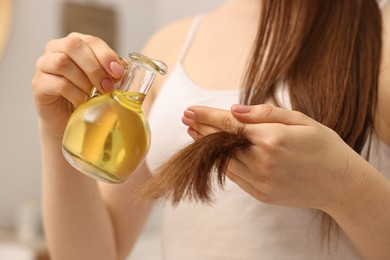 Photo of Woman applying oil hair mask at home, closeup