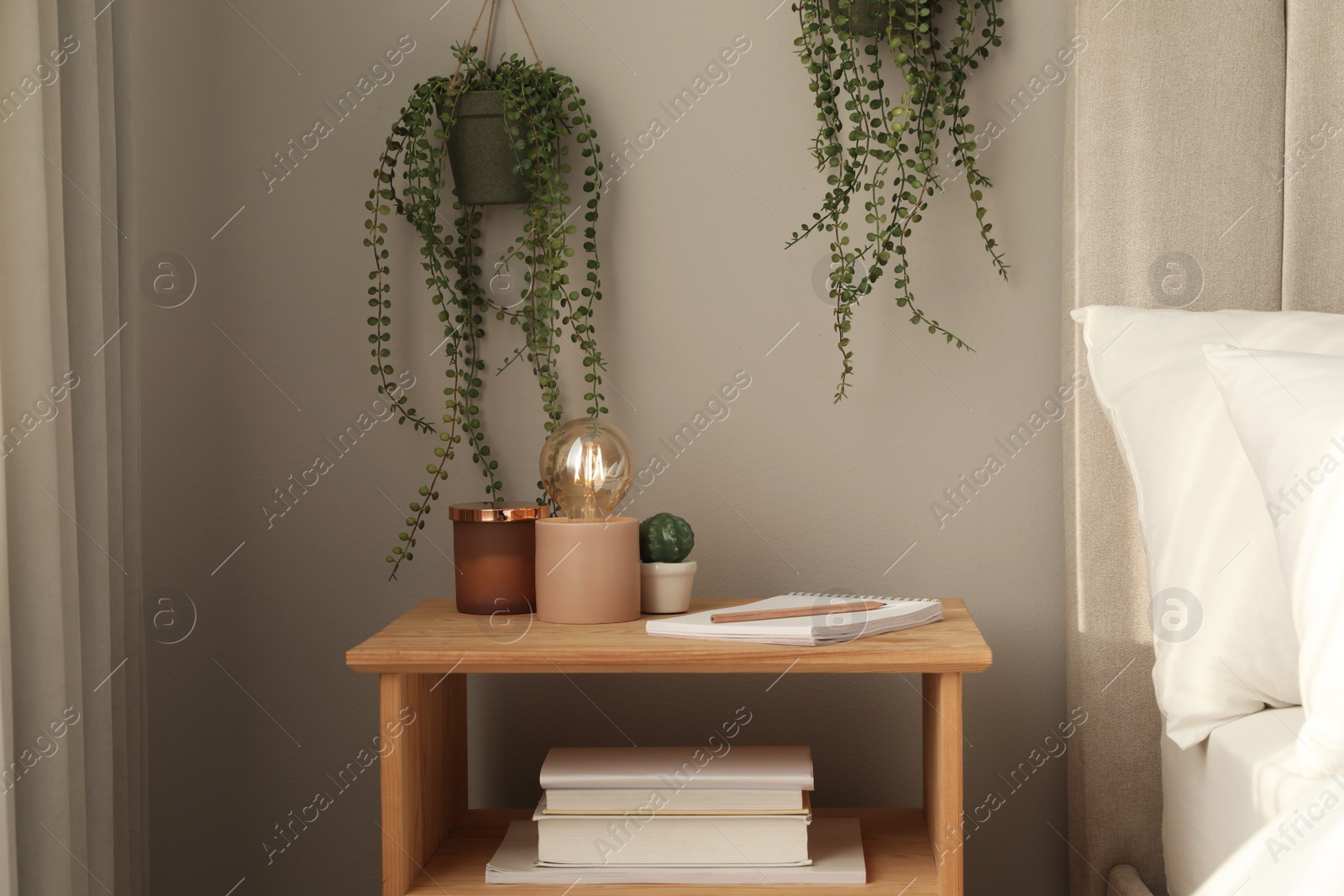 Photo of Stylish lamp and decor on wooden nightstand in bedroom. Interior element