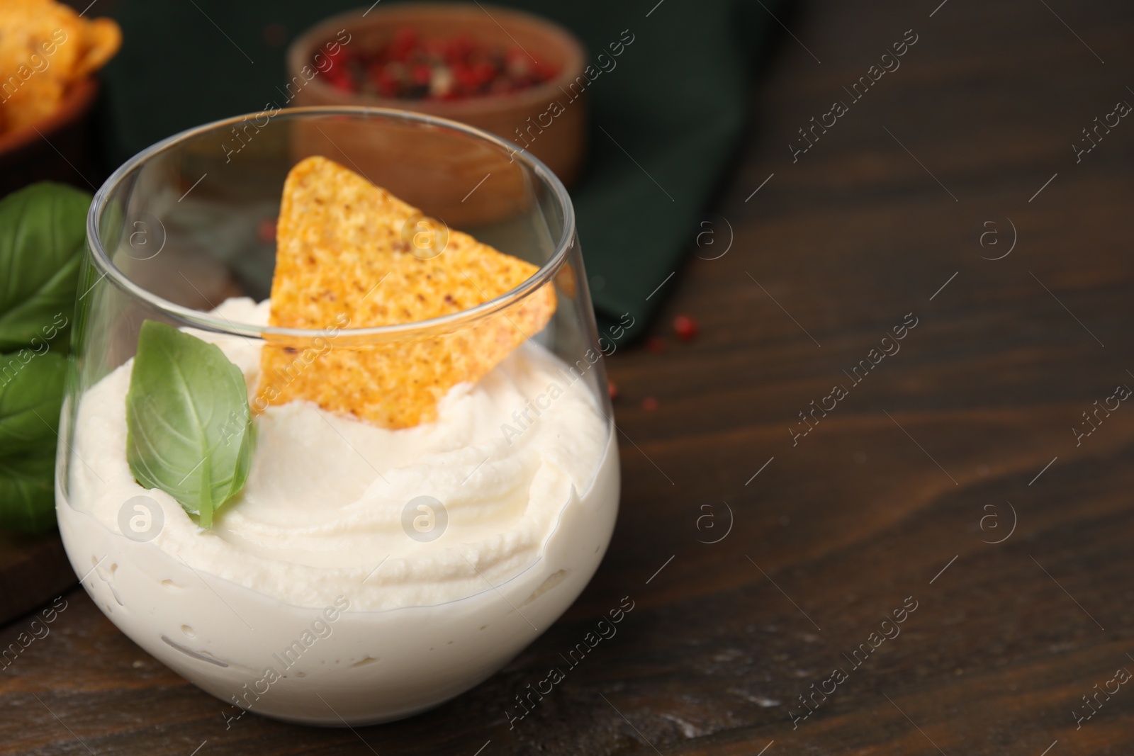 Photo of Delicious tofu sauce served with nachos chip on wooden table, closeup. Space for text