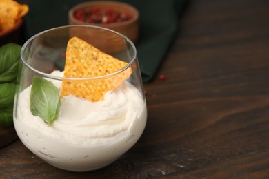 Photo of Delicious tofu sauce served with nachos chip on wooden table, closeup. Space for text