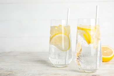 Soda water with lemon slices on white wooden table. Space for text